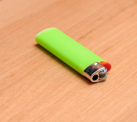 Green lighter on the wooden floor. A green lighter on a wooden tableの写真素材