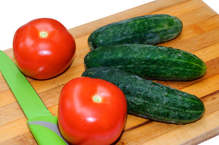 Fresh tomatoes and cucumbers on wooden Board for cuttingの写真素材