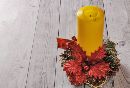 A yellow candle and a New Year pine wreath on an old wooden background.の写真素材