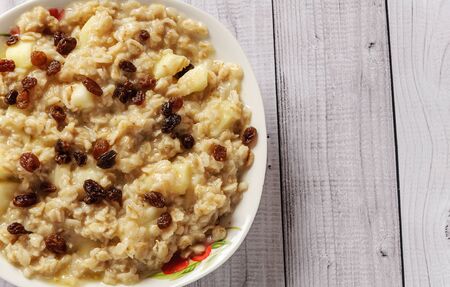 Oatmeal with apple and raisins against the background of the old tree. Muesli with an apple and raisins.の写真素材