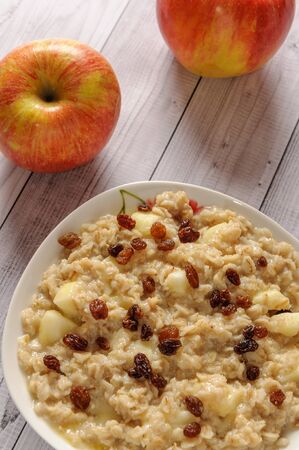 Oatmeal with apple and raisins against the background of the old tree. Muesli with an apple and raisins.の写真素材