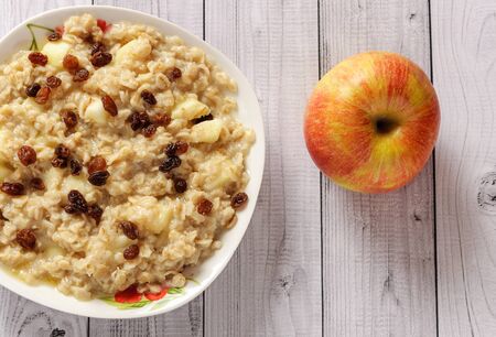 Oatmeal with apple and raisins against the background of the old tree. Muesli with an apple and raisins.の写真素材