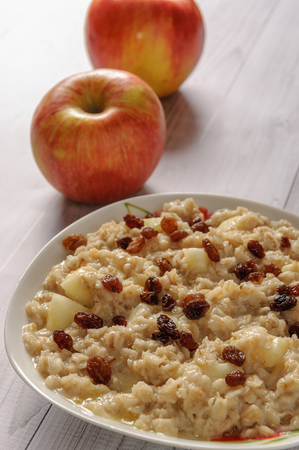 Oatmeal with apple and raisins against the background of the old tree. Muesli with an apple and raisins.の写真素材