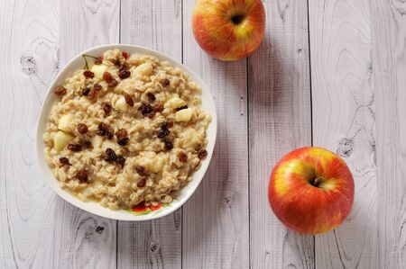 Oatmeal with apple and raisins against the wooden backgroundの写真素材