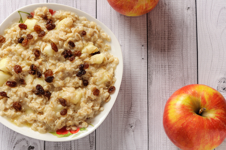 Oatmeal with apple and raisins against the wooden backgroundの写真素材
