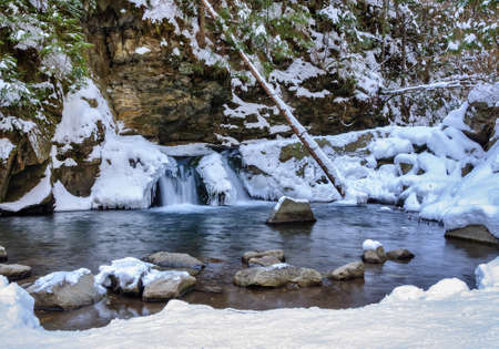 Waterfall in winter. Mountain river and snow on the mountain slopesの写真素材