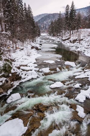 Winter landscape. Mountain river flows from the rocks. Snow and mountain riverの写真素材