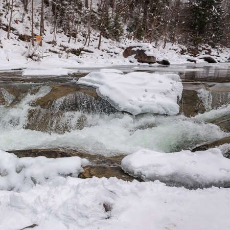 Winter landscape. Mountain river flows from the rocks. Snow and mountain river.の写真素材