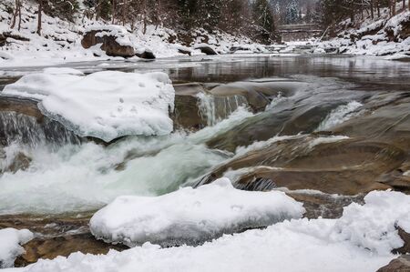 Winter landscape. Mountain river flows from the rocks. Snow and mountain river.の写真素材