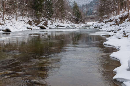 Winter landscape. Mountain river flows from the rocks. Snow and mountain river.の写真素材