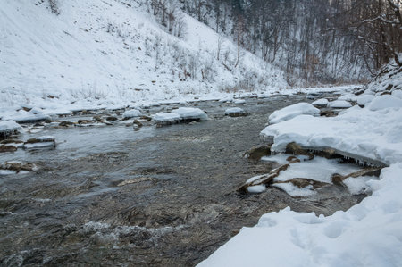 Winter landscape. Mountain river flows from the rocks. Snow and mountain river.の写真素材