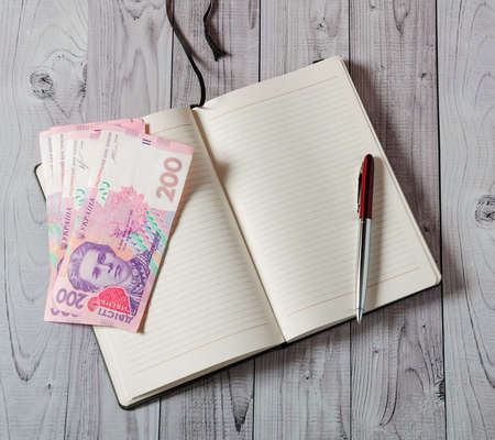 Notepad, pen and money on a light wooden background.の写真素材
