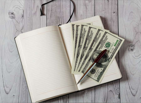 Notepad, pen and money on a light wooden backgroundの写真素材