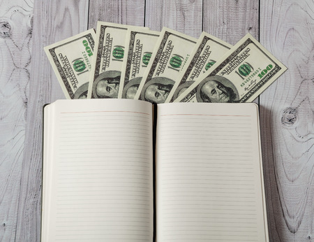 Notepad, pen and money on a light wooden backgroundの写真素材