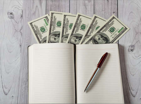 Notepad, pen and money on a light wooden backgroundの写真素材