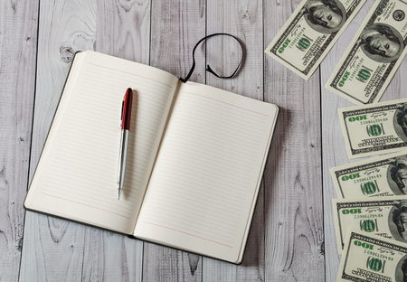 Notepad, pen and money on a light wooden backgroundの写真素材