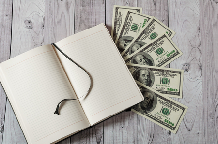 Notepad, pen and money on a light wooden backgroundの写真素材