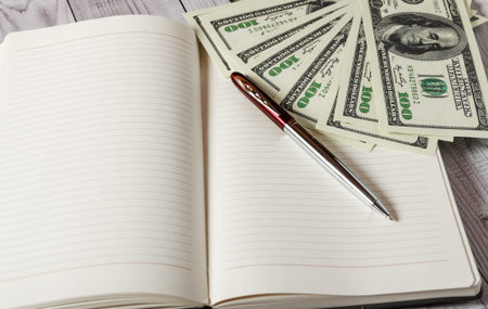 Notepad, pen and money on a light wooden background.の写真素材