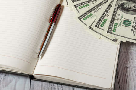Notepad, pen and money on a light wooden background.の写真素材