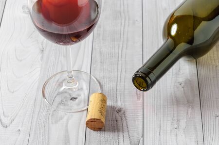 Red wine in a glass and a bottle on a light wooden table.の写真素材