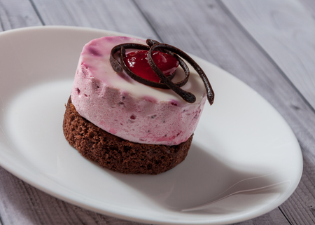 Fresh cherry cake round shape on a light wooden background. Biscuit cake on a wooden tableの写真素材