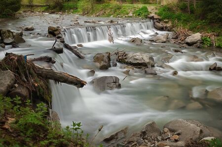 The mountain river flows through a green fairy forest.の写真素材