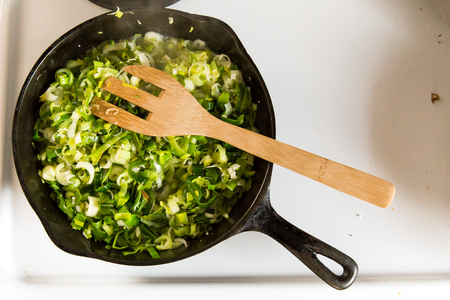 Cooking leeks and onions in a cast iron pan.の写真素材