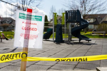 A playground closed sign due to COVID-19 prevention measures infront of a small playground.の写真素材