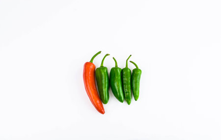 Red chilli on row of green chillies on white backgroundの写真素材