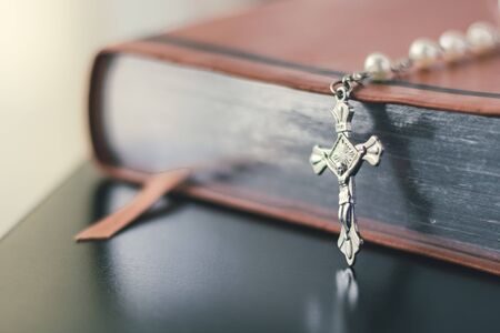 A brown leather bible is placed on a shiny and reflective black table top.の写真素材