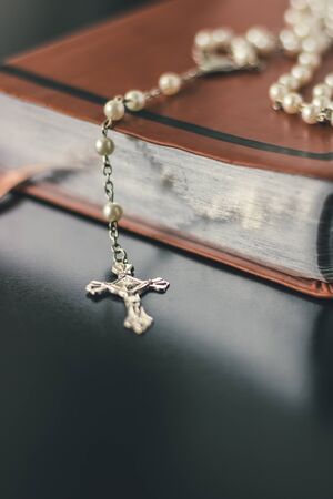 A brown leather bible is placed on a shiny and reflective black table top.