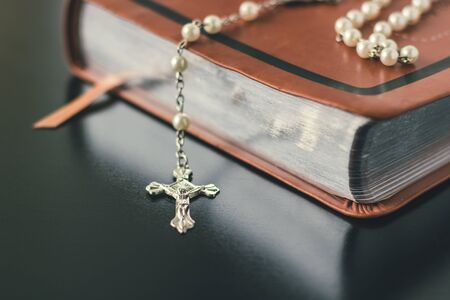 A brown leather bible is placed on a shiny and reflective black table top.の写真素材
