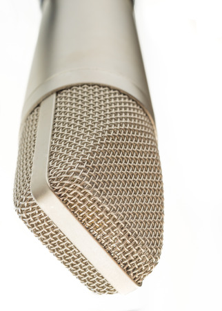 An old fashioned silver microphone is placed on a stand upside down. The background is all whiteの写真素材