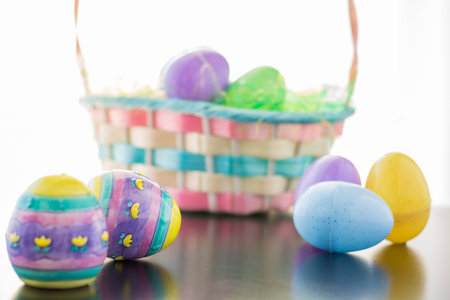 An Easter Basket is filled with Easter Eggs. Ceramic a plastic decorated eggs lay in front of the...