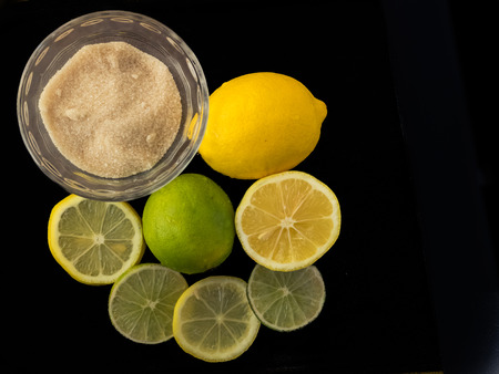 Freshly sliced lemons and limes are decoritively displayed on a black background.の写真素材