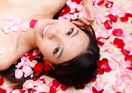 Asian beauty Girl smiling close-up with rose background, Beautiful young woman touching her face looking to the cameraの写真素材