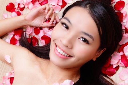 Asian beauty Girl smiling close-up with rose background, Beautiful young woman touching her face looking to the cameraの写真素材