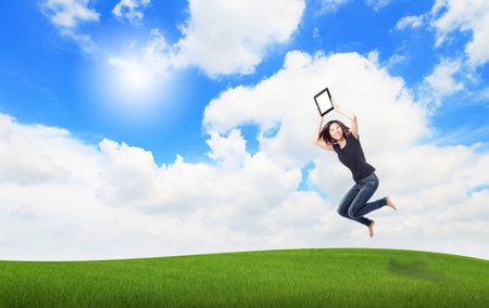 Happy Girl Jump and show touch pad computer on the meadow with blue sky and white cloud, , for cloud...