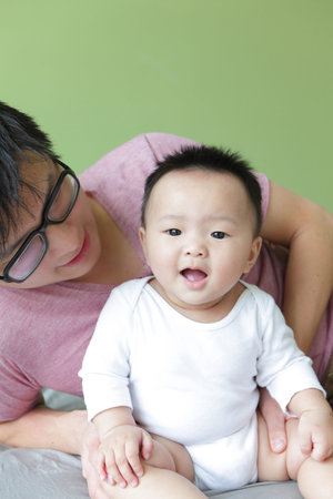 Young Father Happy Play with His Baby (an asian family) with green home background