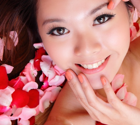 beauty Girl smiling face and hand touch her face close up with red rose background, model is a asian beautyの写真素材