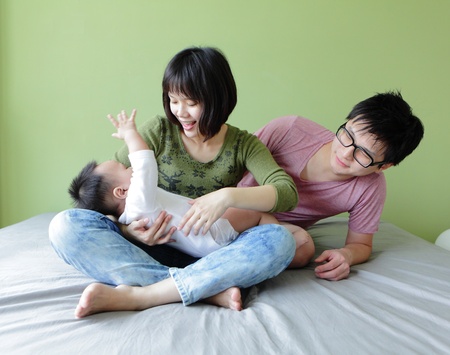happy family, mother ,father and their baby with green background, model are asian familyの写真素材