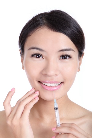 Beautiful woman smile recieving a injection in her lip isolated on white background, model is a asian beautyの写真素材