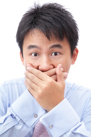 business man making the speak no evil gesture isolated on white background. young businessman covering his mouth with his hand, model is a asianの写真素材