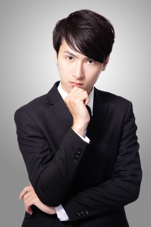 portrait of handsome business man with hand on chin, looking at camera on gray background, asian male modelの写真素材