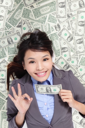 Young business woman happy show ok hand with money and lying on money bed, asian beauty modelの写真素材