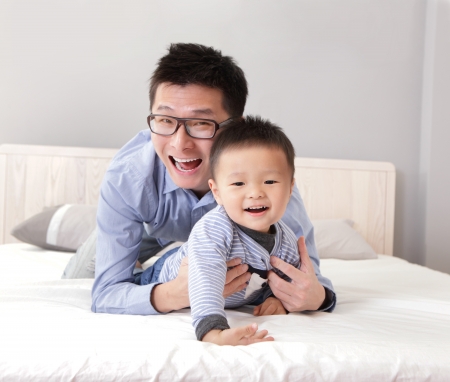 young father play with his son boy on the bed at home, asian lifestyleの写真素材