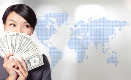 Globe business concept - happy business woman with earned dollar bills us money with world map background, asian beauty modelの写真素材