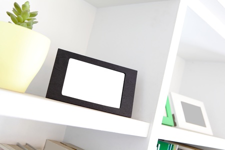 blank photo frame with copy space on white bookshelf at homeの写真素材