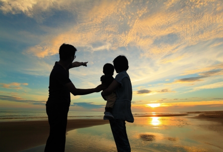 silhouette of family watching the sunrise on the beachの写真素材