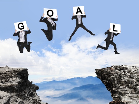 businessman overcome danger precipice and jumping with GOAL text billboard on the mountainの写真素材